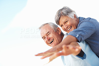 Buy stock photo Cheerful man piggybacking mature woman outdoors with hands outstretched