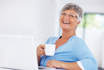 Buy stock photo Smiling mature woman enjoying coffee while using laptop at home