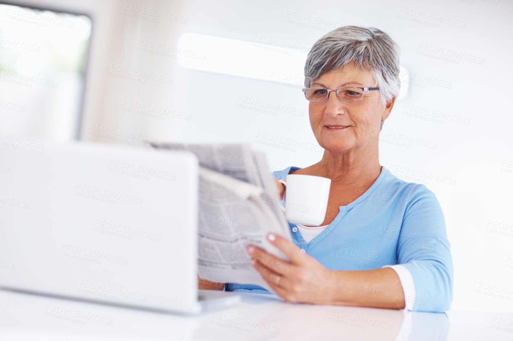 Buy stock photo Senior woman, drinking coffee and reading newspaper for press story, information or relax in retirement. Tea, home or person with news article for morning routine, politics or report update on laptop