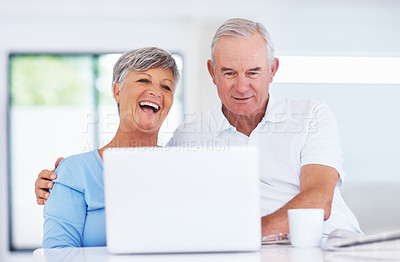 Buy stock photo Cheerful mature couple smiling while using laptop at home