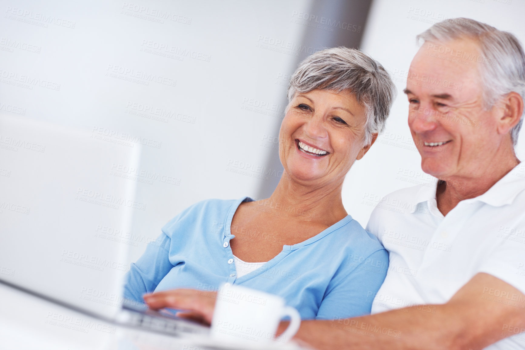 Buy stock photo Elderly woman, man and laptop with coffee, smile and morning with reading, search and email in home. Happy couple, computer and senior people in kitchen with notification, relax and click in house