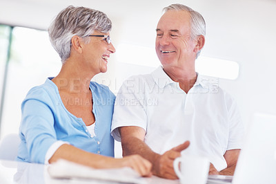 Buy stock photo Happy mature couple looking at each other while using laptop at home