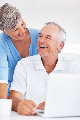 Buy stock photo Cheerful mature man and woman enjoying time together at home while using laptop
