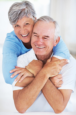 Buy stock photo Portrait of cheerful mature couple embracing while relaxing at home
