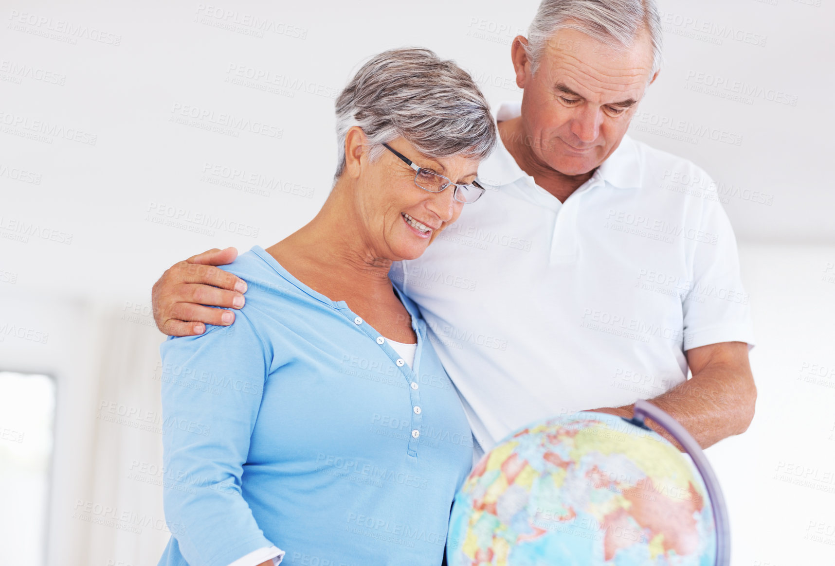 Buy stock photo Happy mature couple planning world tour while looking at globe
