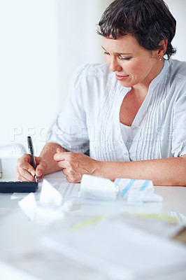 Buy stock photo Mature female executive busy calculating taxes in office