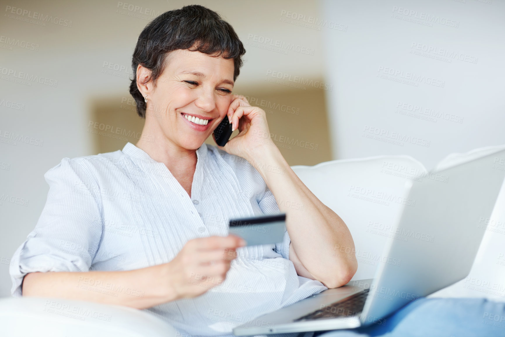 Buy stock photo Mature woman with credit card and laptop talking on cellphone while shopping online