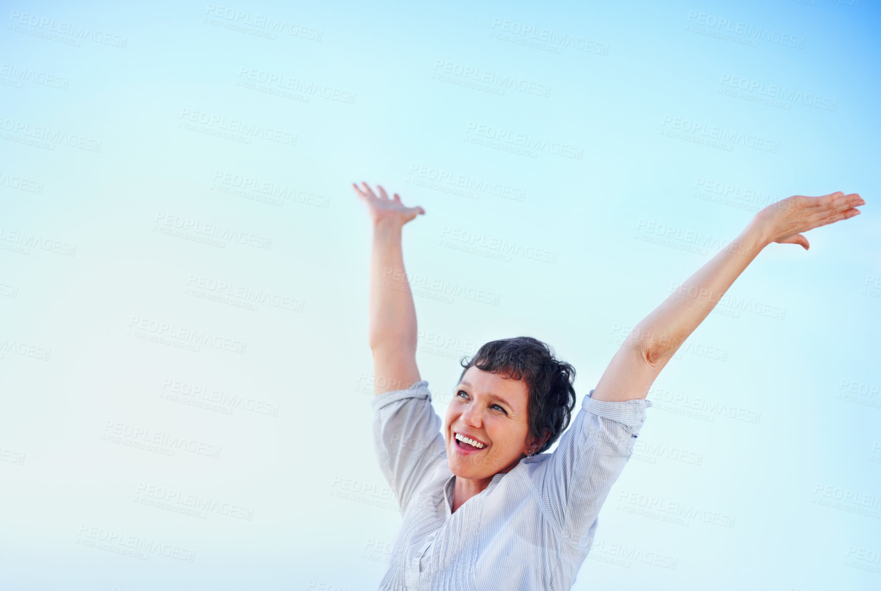 Buy stock photo Happy mature woman enjoying freedom against blue sky with arms raised