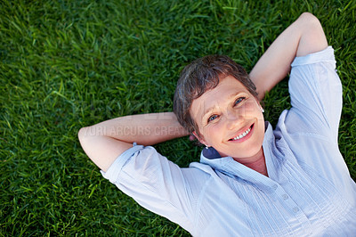Buy stock photo Top view of beautiful mature woman smiling while lying on grass