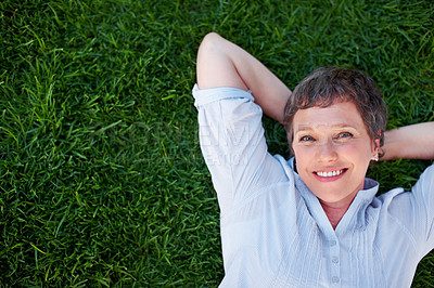 Buy stock photo Top view of mature woman smiling while lying on grass