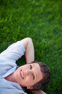 Buy stock photo Portrait of relaxed mature woman smiling while lying on grass