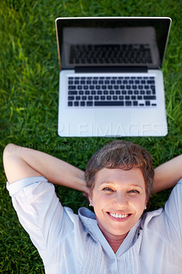 Buy stock photo Top view relaxed mature female with laptop smiling while lying on grass