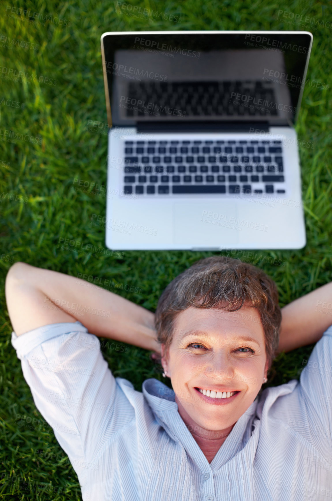 Buy stock photo Top view relaxed mature female with laptop smiling while lying on grass