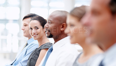 Buy stock photo Business partners sit in a row at a meeting with focus on a female looking at you