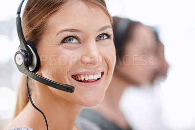 Buy stock photo Pretty call operator in her office besides some colleagues and looking up with a smile