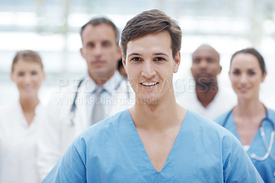 Buy stock photo Happy male doctor smiling at the camera with his colleagues in the background - portrait