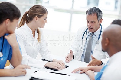 Buy stock photo Group of doctors sitting around a boardroom table having a discussion 