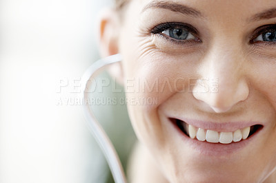 Buy stock photo Closeup of a beautiful smiling doctor with a stethoscope in her ear