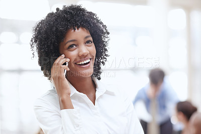 Buy stock photo An african woman using her cellphone in the office with her colleagues in the background