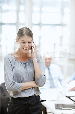 Buy stock photo A beautiful woman using her cellphone in the office with her colleagues in the background