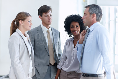 Buy stock photo Four business colleagues stand in their workplace and discuss upcoming projects