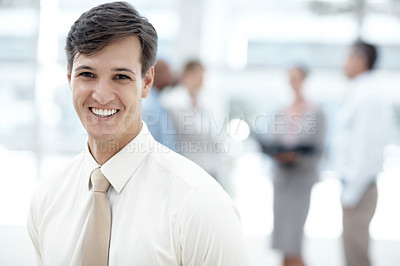 Buy stock photo Shot of a businessman standing in an office lobby with colleagues in the background
