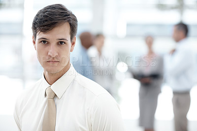 Buy stock photo Shot of a businessman standing in an office lobby with colleagues in the background