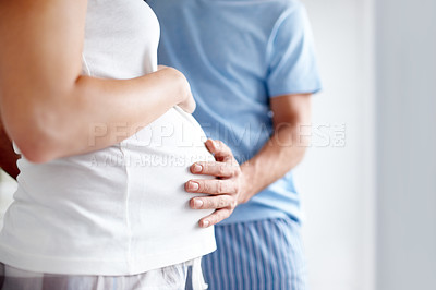 Buy stock photo Side view of a pregnant woman holding her belly as the husband touches it in affection