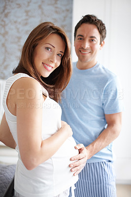 Buy stock photo Happy young pregnant woman standing with her husband at home
