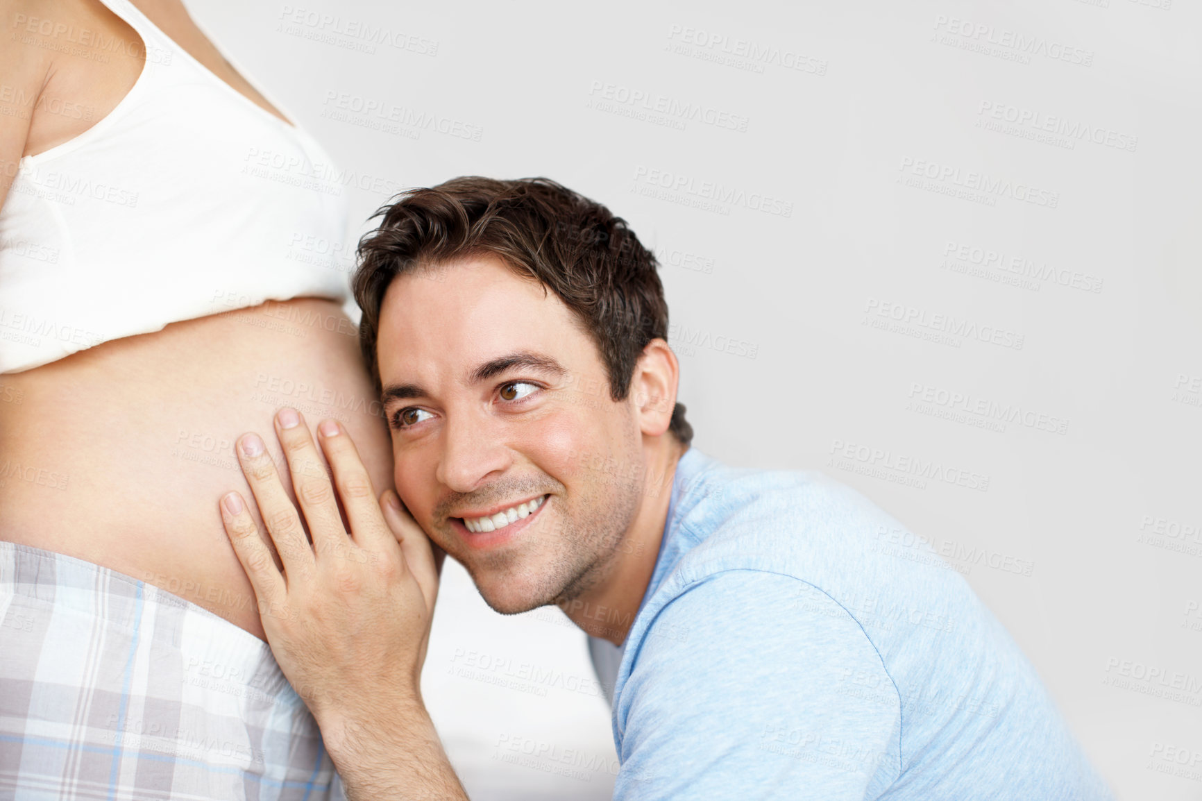 Buy stock photo Happy couple, father and listening to stomach of pregnant woman for paternity, health or prenatal expectation. Smile, tummy and dad hearing baby for support, love and care on white studio background