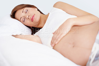 Buy stock photo Young pregnant woman sleeping on her bed with her arm resting on her belly