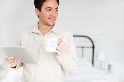 Buy stock photo A handsome young man drinking coffee and holding his digital tablet - Copyspace