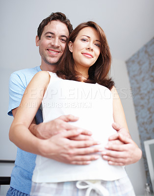 Buy stock photo Low-view portrait of two expectant parents holding her baby bump