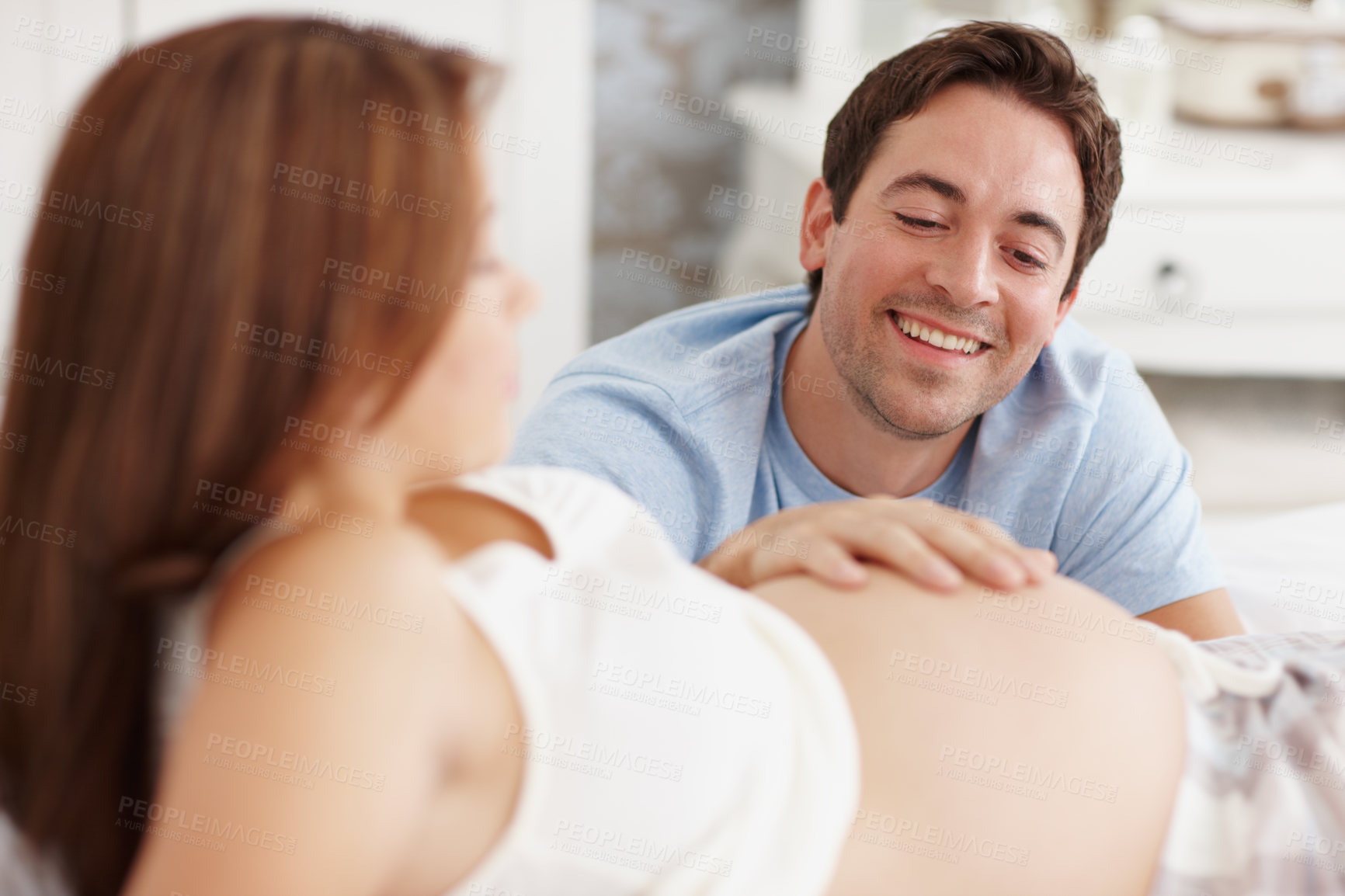 Buy stock photo An excited young man touching his pregnant wife's stomach