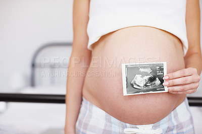 Buy stock photo Cropped closeup of an expectant mother holding an ultrasound picture over her baby bump
