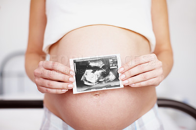 Buy stock photo Cropped closeup of an expectant mother holding an ultrasound picture over her baby bump