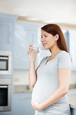 Buy stock photo Pregnancy, woman and drinking water in kitchen for health, wellness and hydration for growth. Future mom, smile and glass in home for detox, gut cleansing and nourishment with aqua for healthy baby