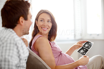 Buy stock photo Young couple looking at a image of their babies sonogram