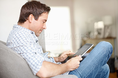 Buy stock photo Young mature man sitting on his sofa at home with this digital tablet