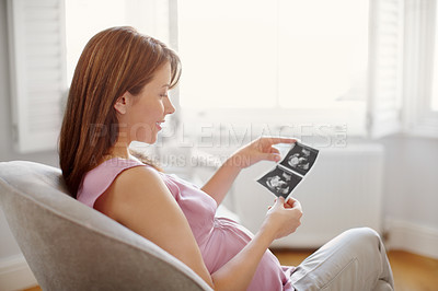 Buy stock photo Pretty young woman looking at her babies sonogram while sitting at home