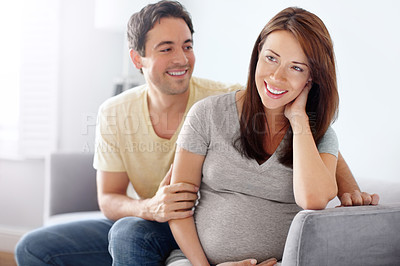 Buy stock photo Attractive young expecting couple sitting in their living room