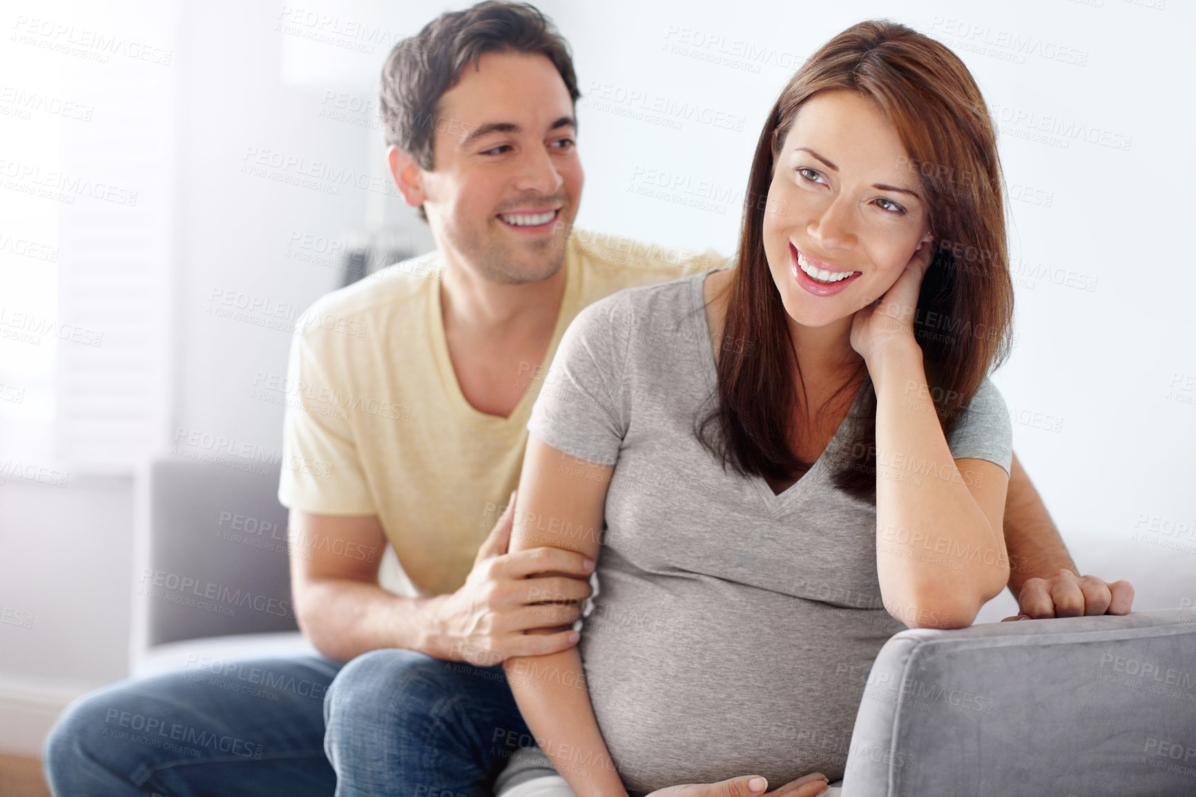 Buy stock photo Attractive young expecting couple sitting in their living room