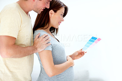 Buy stock photo Young expecting couple holding a pink and blue colour palette wondering what the gender is going to be