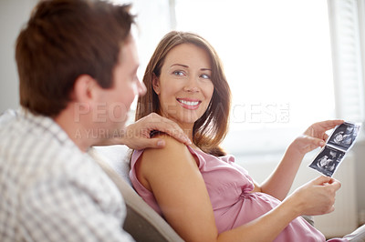 Buy stock photo A beautiful pregnant woman looking at ultrasound scans with her husband - Copyspace