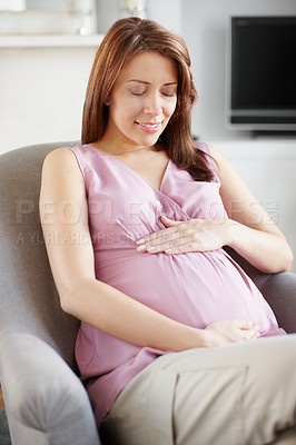 Buy stock photo A glowing pregnant woman looking at her swelling baby bump