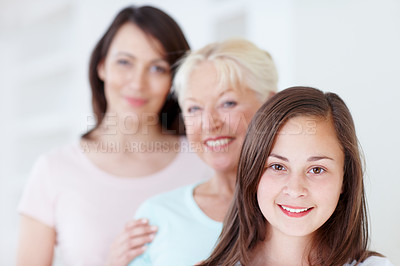 Buy stock photo Portrait of a cute little girl smiling with her grandmother and mother in the background