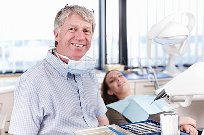 Buy stock photo Portrait of mature dentist smiling with female patient in background