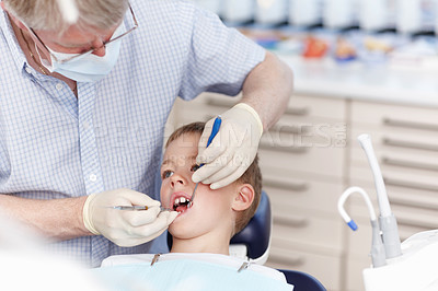 Buy stock photo Portrait of mature dentist working on child's teeth in clinic