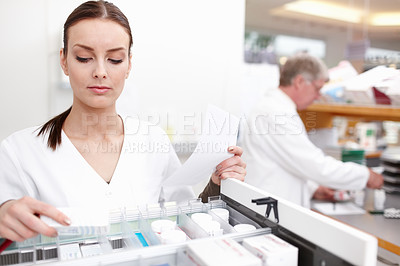 Buy stock photo Portrait of female pharmacist checking medicines with colleague working in background