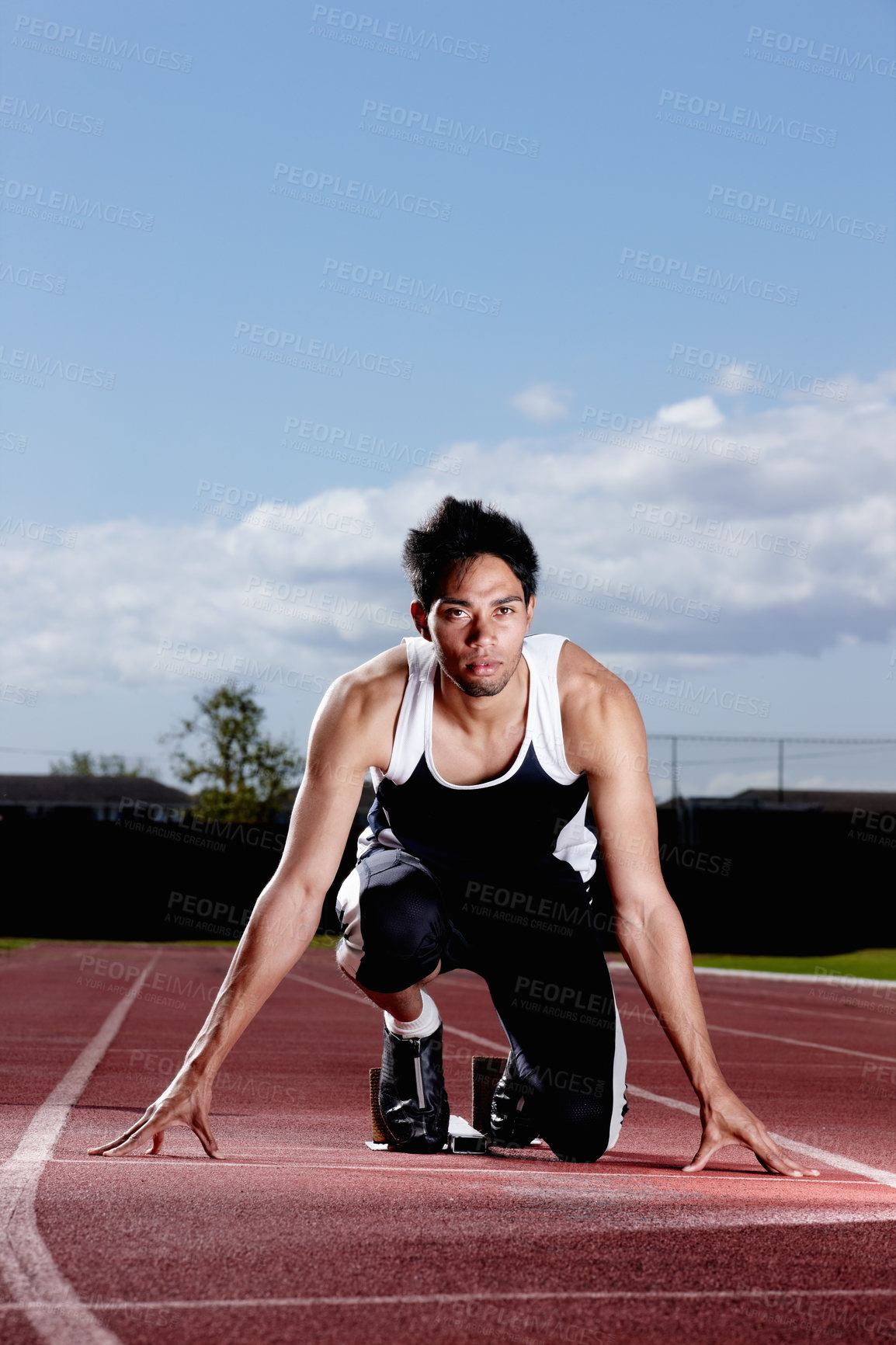 Buy stock photo Runner, fitness and man at starting block at stadium track for race, sports competition or training with concentration. Field, ready and athlete prepared for sprint, speed or fast performance outdoor